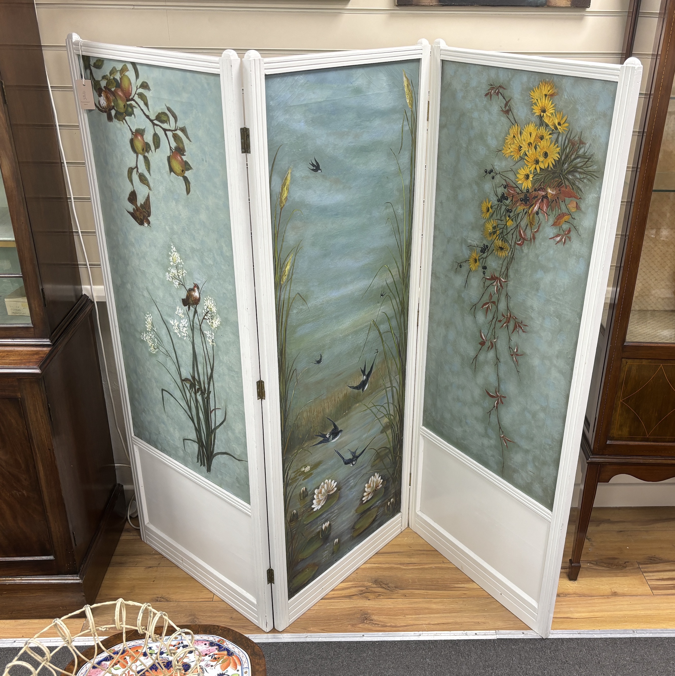 An early 20th century, painted three fold dressing screen, the canvas panels decorated with birds and fruiting branches, each panel width 62cm, height 157cm